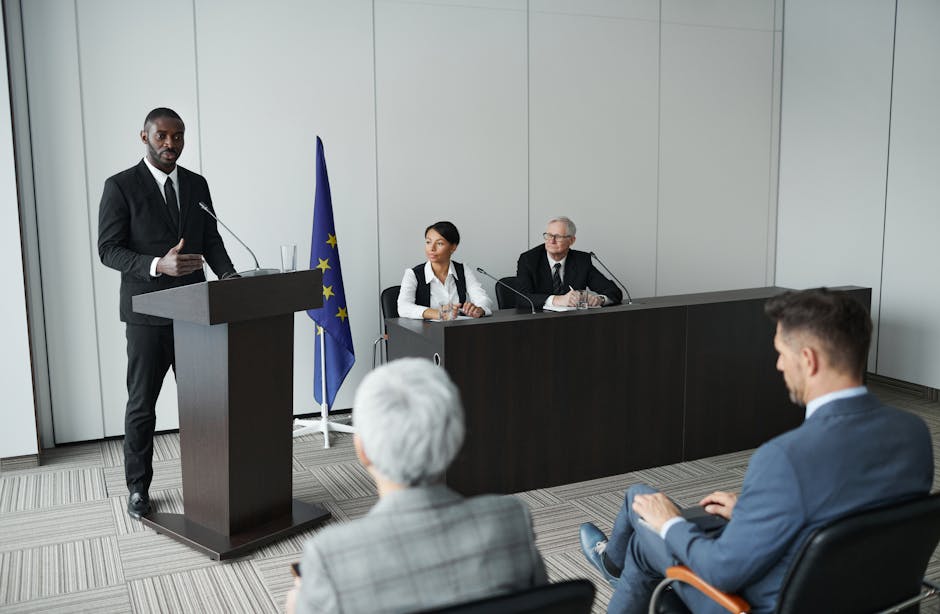 A well-lit speaker at a press conference podium with balanced lighting illuminating their face