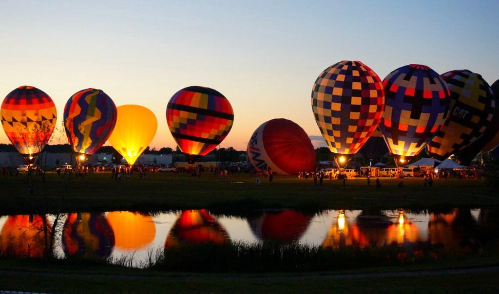 A beautiful night scene of the Balloon Glow event at the Albuquerque Balloon Fiesta, with illuminated balloons against a twilight sky