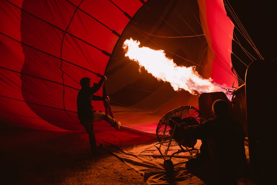 A close-up view of a hot air balloon being inflated, with crew members working around it and spectators watching in excitement