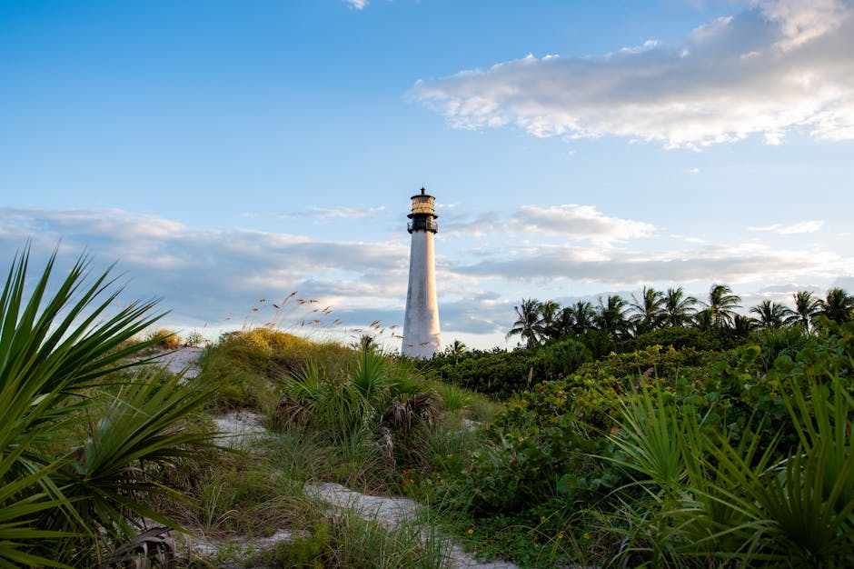 The historic Cape Florida Lighthouse bathed in soft morning light, surrounded by lush greenery and sandy shores