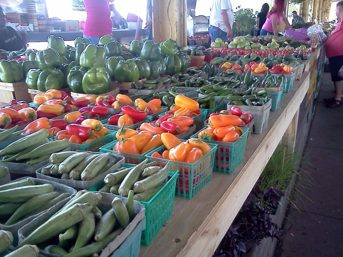 Colorful displays of fresh produce and artisanal goods at the Dallas Farmers Market with vendors and customers