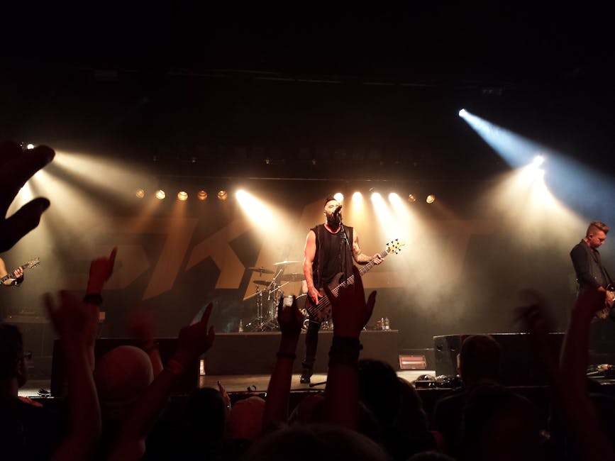 A guitarist intensely strumming their guitar on stage with a wild, energetic crowd in the background