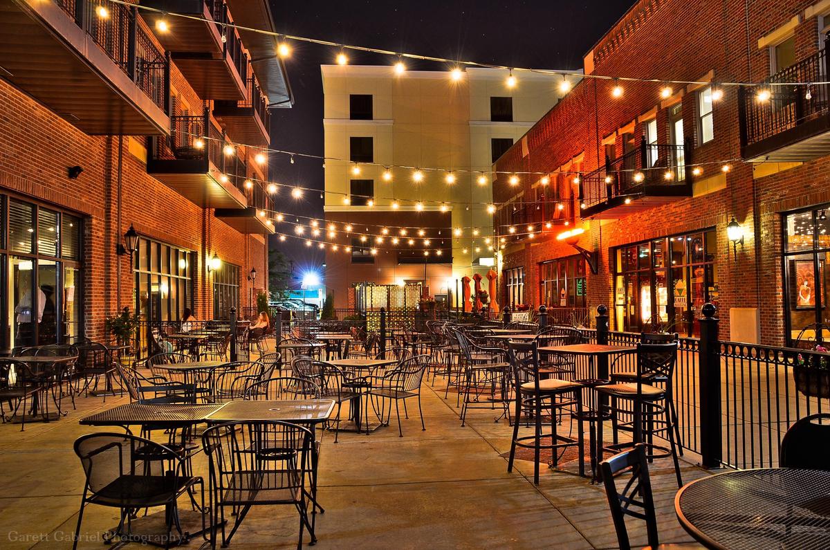 Bustling nightlife scene on Larimer Street in Denver, with people enjoying outdoor cafes and twinkling lights on historic buildings