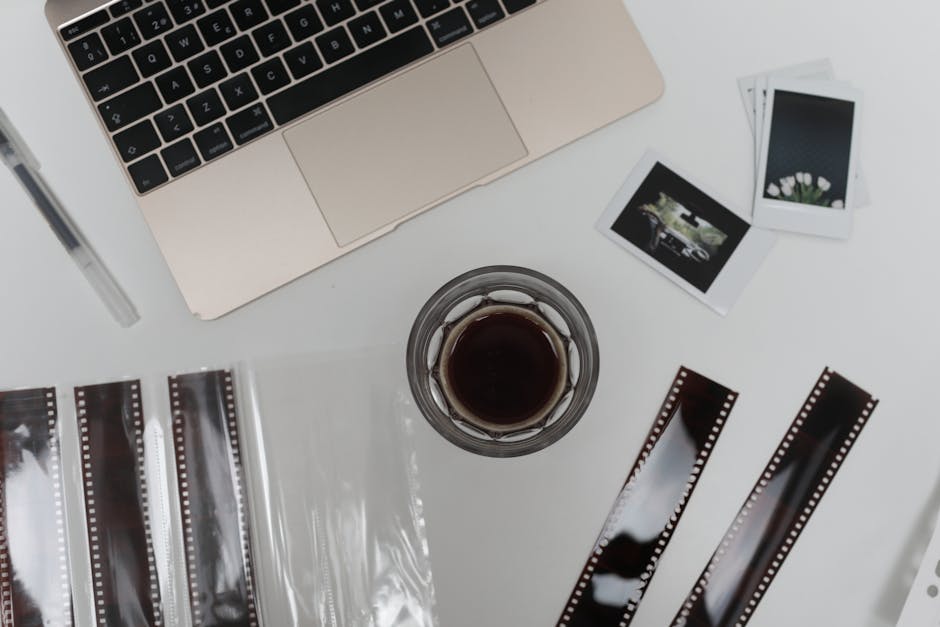 A desk with various photography resources including a laptop showing editing software, camera equipment, and workshop materials